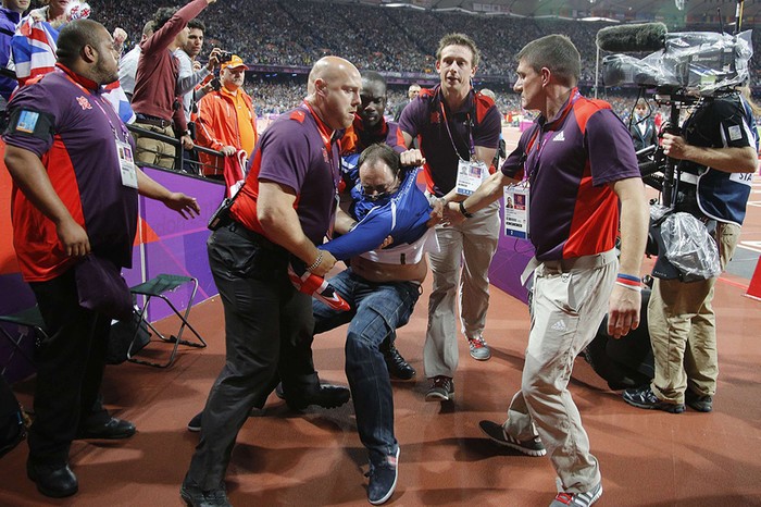 Một fan cuồng bị các nhân viên an ninh giữ lại khi đang cố chạy xuống đường pitch sân Olympic.